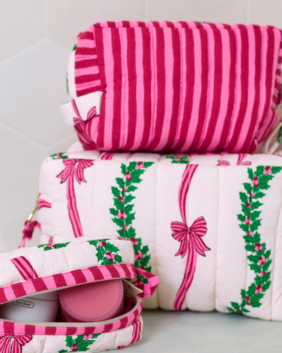 Close-up of the stacked quilted pouches, showing the pink striped pouch and the open pouch with containers inside.
