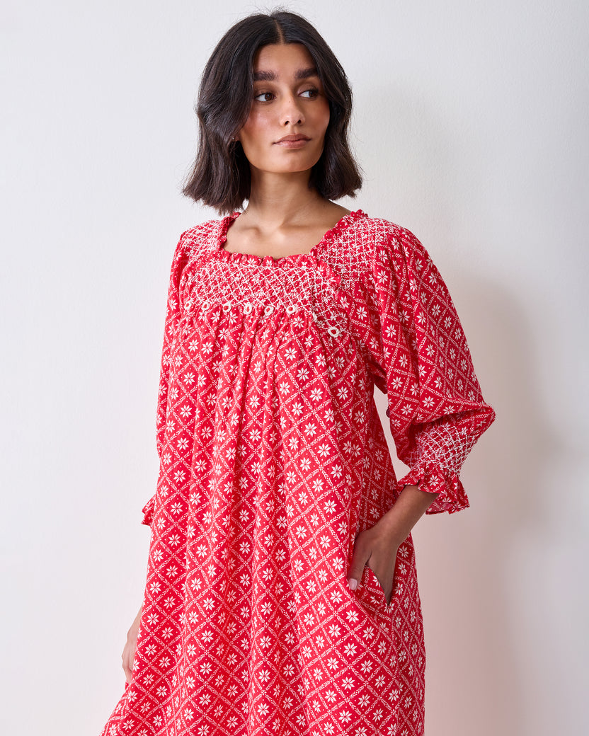 Front three-quarter view of the red patterned Parker nightgown, showing the gathered neckline, buttons, pockets, and sleeve details