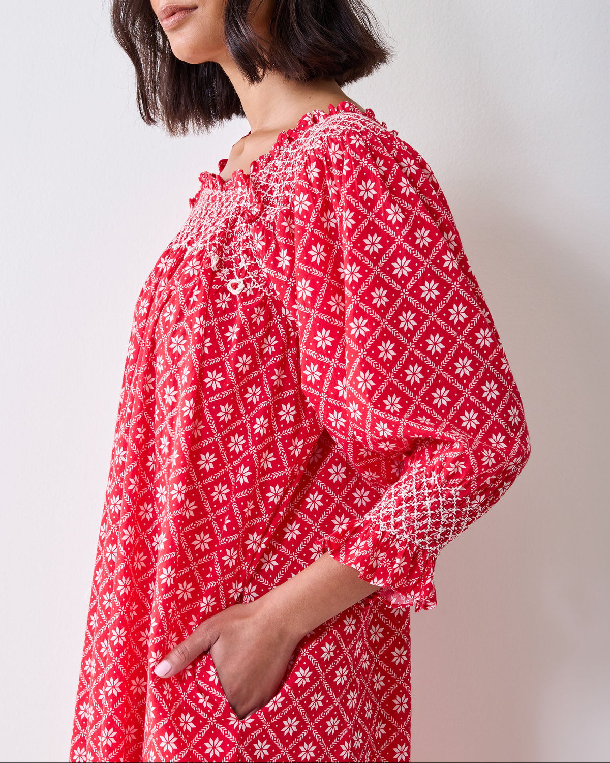 Close view of the red Scandi Snowflake Parker Nightgown, showing its smocked bodice, gathered neckline, embroidered details, and white snowflake print.