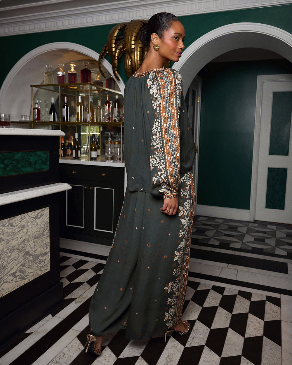 Rear three-quarter view of the spruce Hallie blouse and Sasha pants worn together, showing the patterned sleeves and pant sides.
