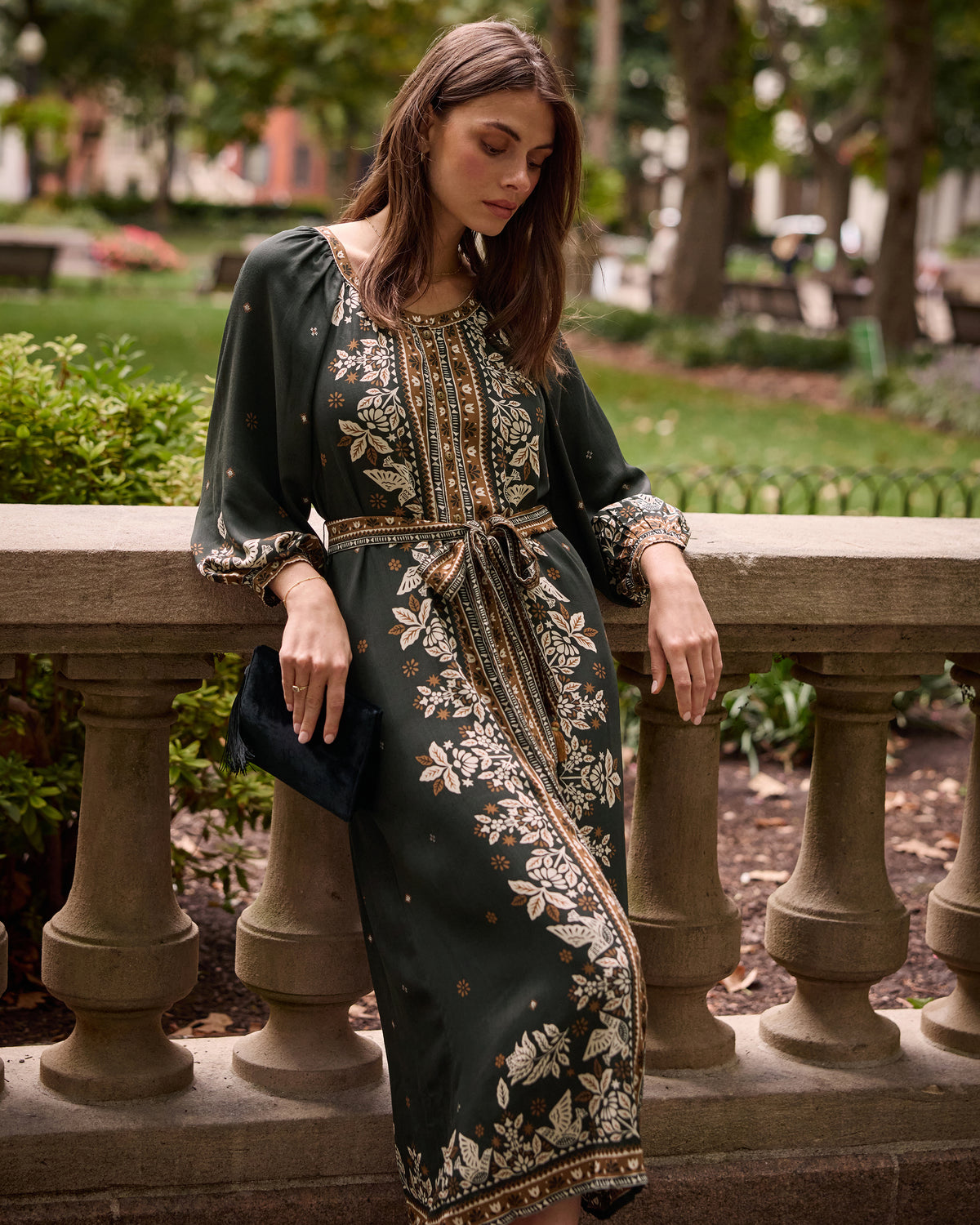 Spruce Hunter midi dress with a floral tapestry print, long sleeves, and a matching tie belt, shown outdoors.