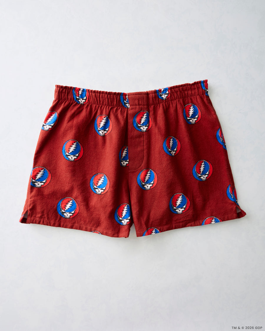 Red boxer shorts laid flat, featuring a repeating circular skull-and-lightning-bolt print and an elastic waistband.