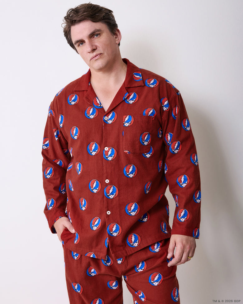 Full-length view of a person wearing a red long-sleeved pajama set with a repeating skull-and-lightning-bolt print.