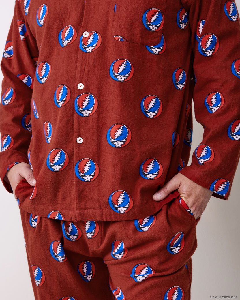 Close-up of the red pajama shirt and pants showing the buttons, pockets, and repeating skull-and-lightning-bolt print.
