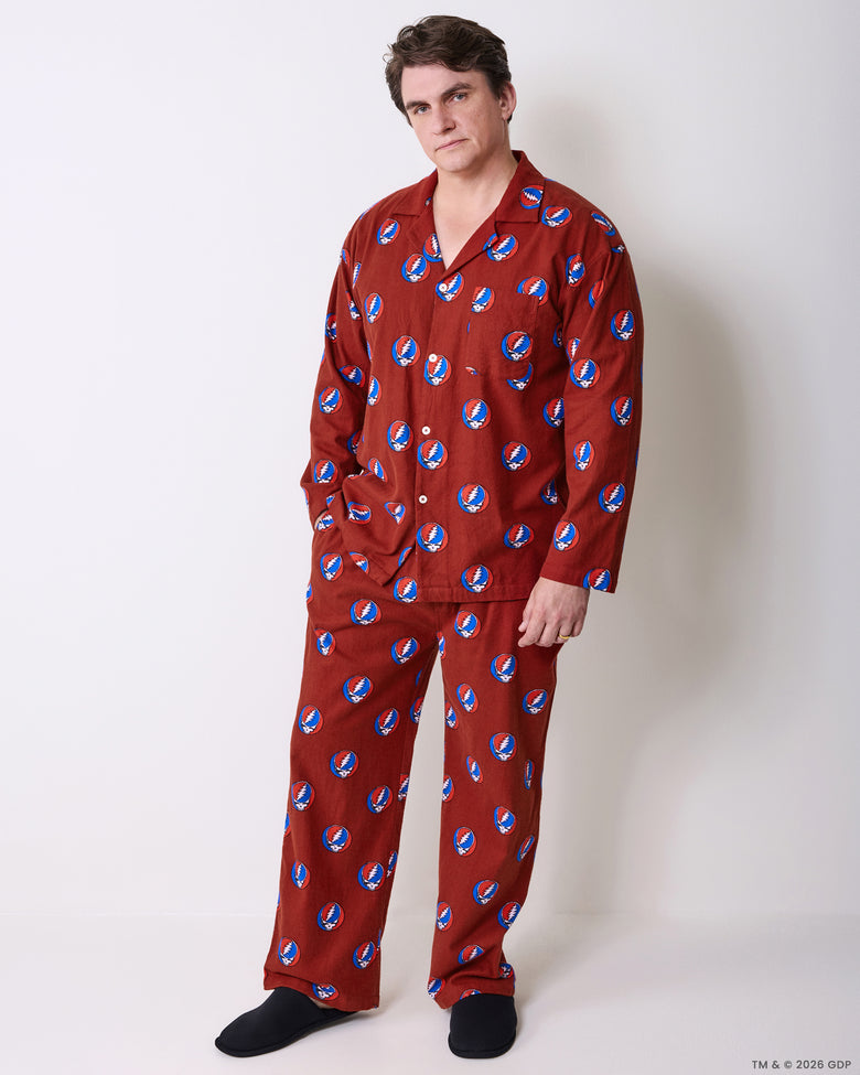 Full-length view of a person wearing a red long-sleeved pajama set with a repeating skull-and-lightning-bolt print.