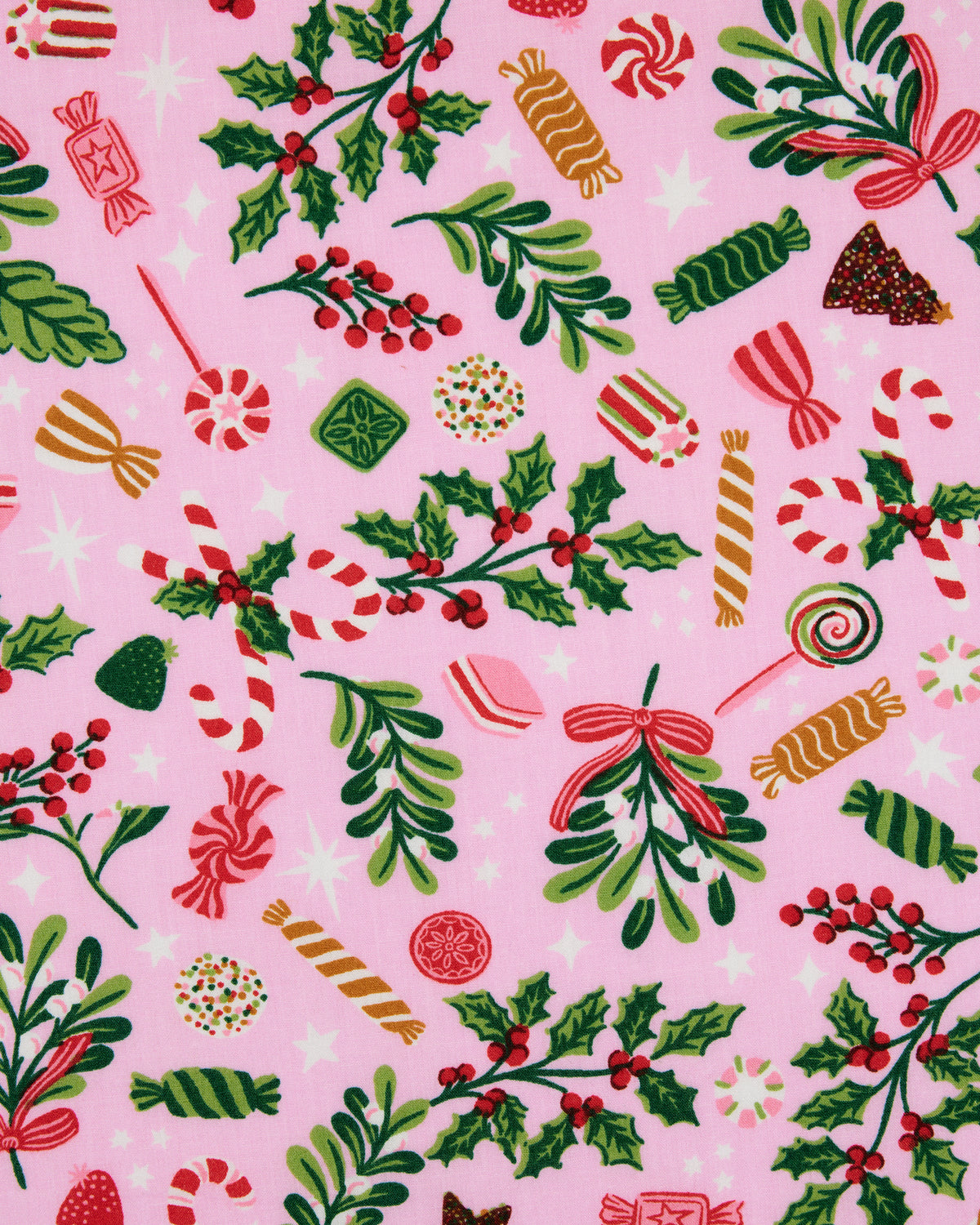 Close-up of pink fabric with candy, holly, greenery, and holiday ornament motifs.