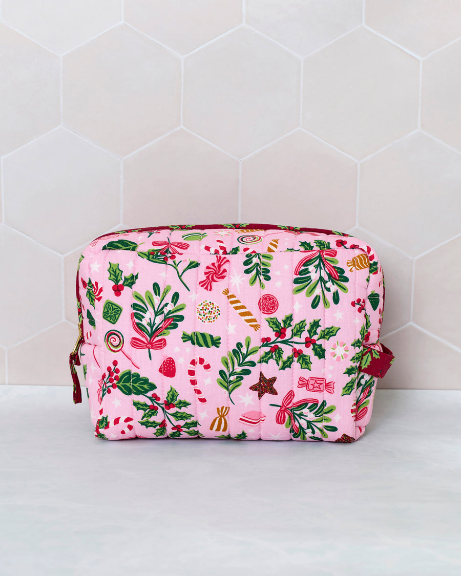 Candy pink quilted pouch with a colorful holiday candy, holly, and foliage print, shown upright from the front.