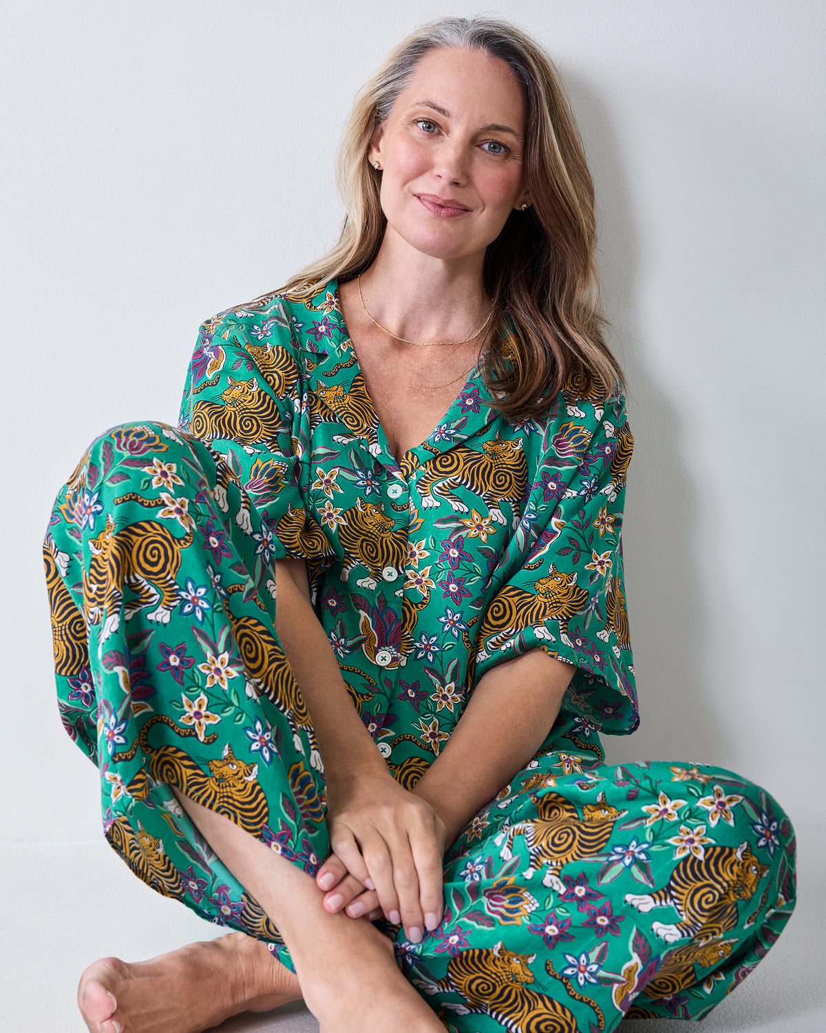 Person seated wearing the Royal Teal Tibetan Tigress Wildest Dreams pajama set, showing the button-front top and matching pants.