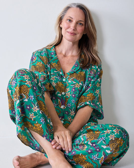 Person seated wearing the Royal Teal Tibetan Tigress Wildest Dreams pajama set, showing the button-front top and matching pants.