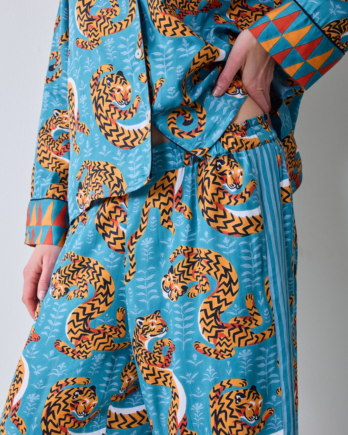 Close-up of the Twisted Tiger tall satin pajama set in Persian turquoise, showing the tiger print, button-front top, elastic-waist pants, and pockets.