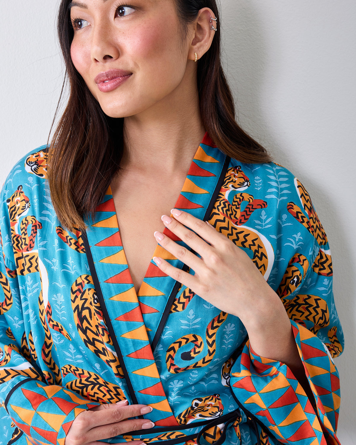 Close-up of the turquoise tiger-print robe's contrasting collar, cuff, and waist tie.