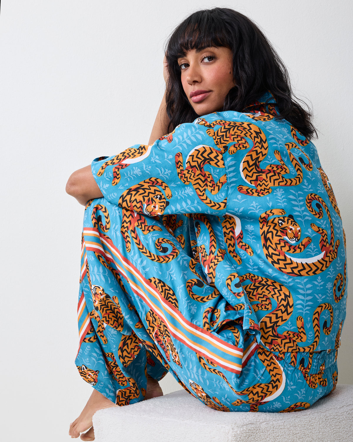Twisted Tiger Wildest Dreams pajama set in Persian turquoise with orange tiger print, shown from the back while seated.
