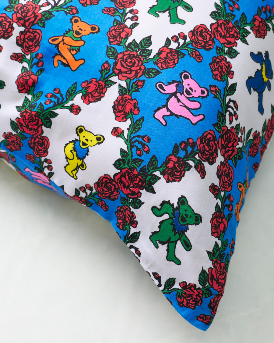 Close-up of the Wandering Rose pillowcase print showing colorful dancing bear figures surrounded by red rose garlands.