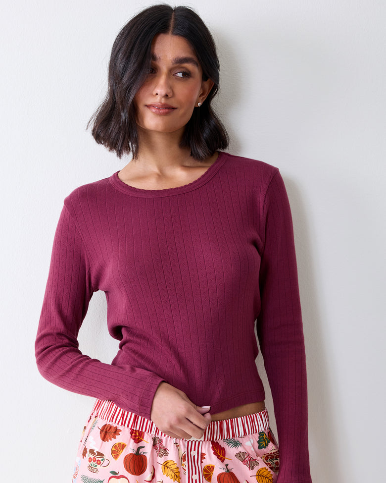 Front view of a wine-colored long-sleeve pointelle top with a scalloped neckline and vertical eyelet pattern.