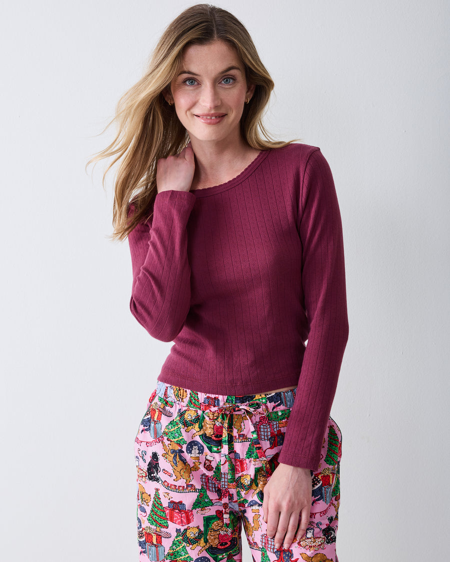 Three-quarter view of a wine-colored long-sleeve pointelle top with a scalloped neckline and vertical eyelet pattern.