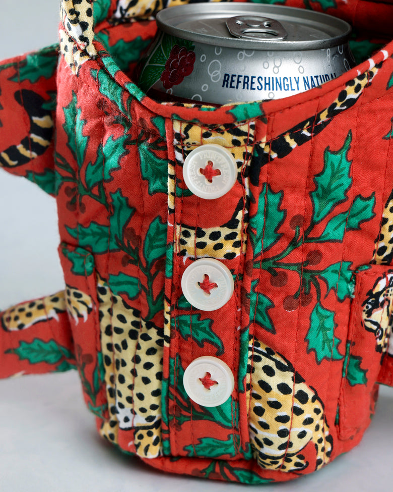 Close-up of the Winter Holly Bagheera quilted pajama cozie around a beverage can, showing its buttoned front and leopard-and-holly print.