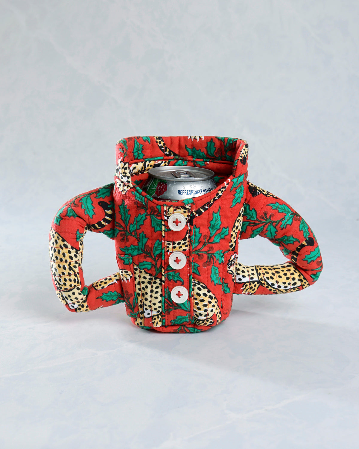 Front view of the Winter Holly Bagheera quilted pajama cozie around a beverage can, with three buttons and two side handles.