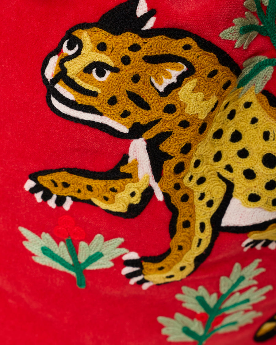 Close-up of the embroidered spotted leopard and greenery decoration on the red Winter Holly Bagheera gift sack.