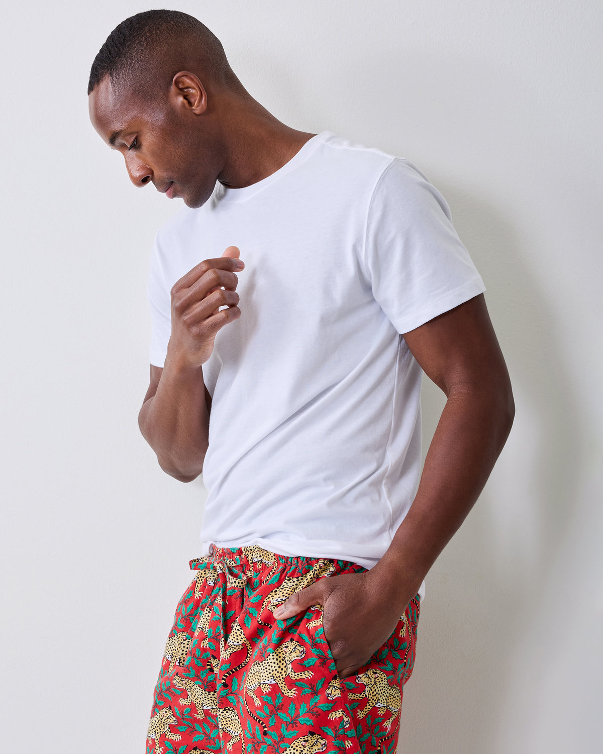 Side view of red pajama pants with a repeating leopard-and-leaf print, worn with a white T-shirt.
