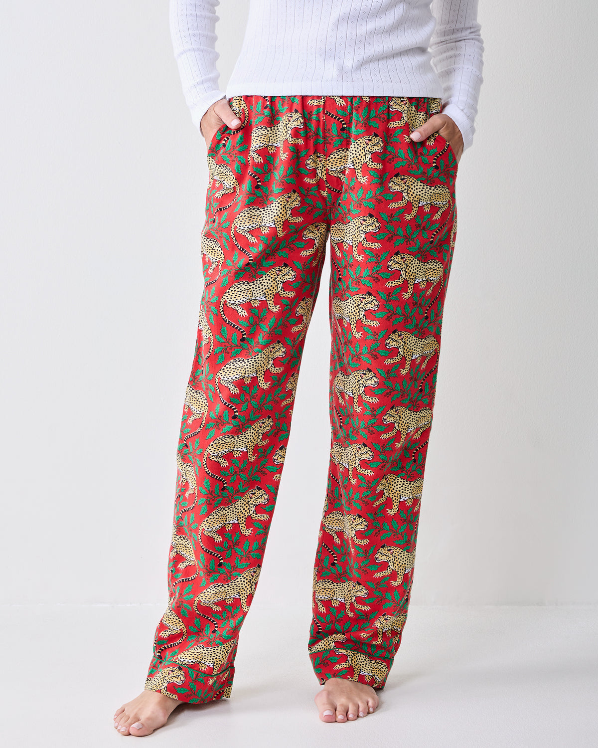 Close front view of Winter Holly Bagheera pajama pants showing the waistband, drawstring, side pockets, and leopard-and-holly print.