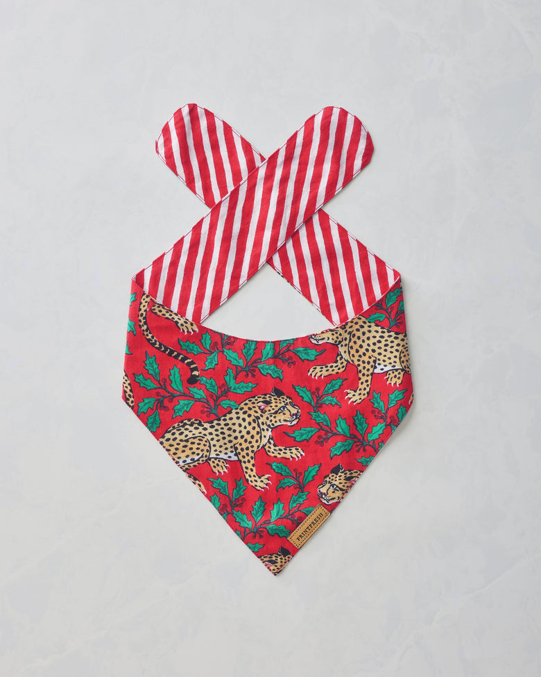 Ruby Winter Holly Bagheera pet bandana laid flat, showing the leopard and holly print with red-and-white striped tie straps.