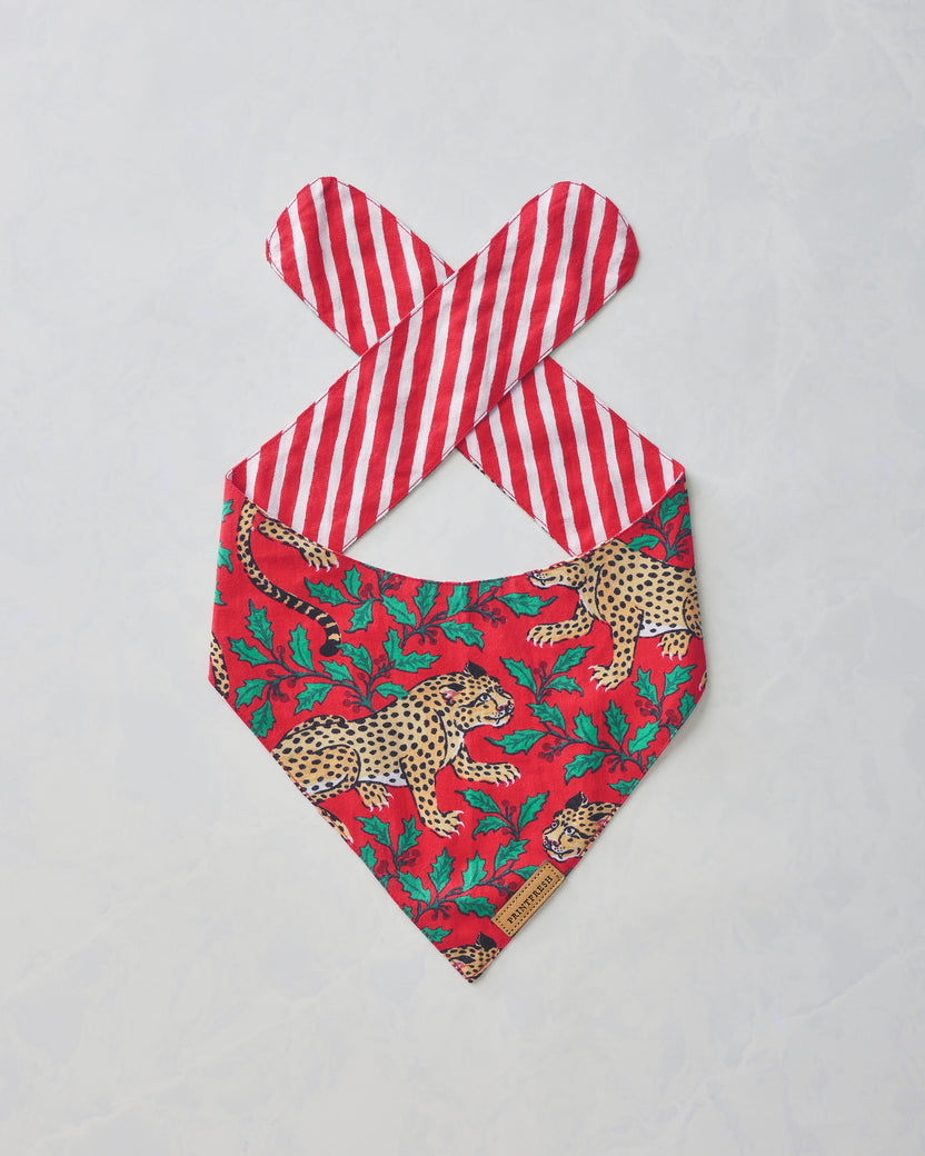 Ruby Winter Holly Bagheera pet bandana laid flat, showing the leopard and holly print with red-and-white striped tie straps.