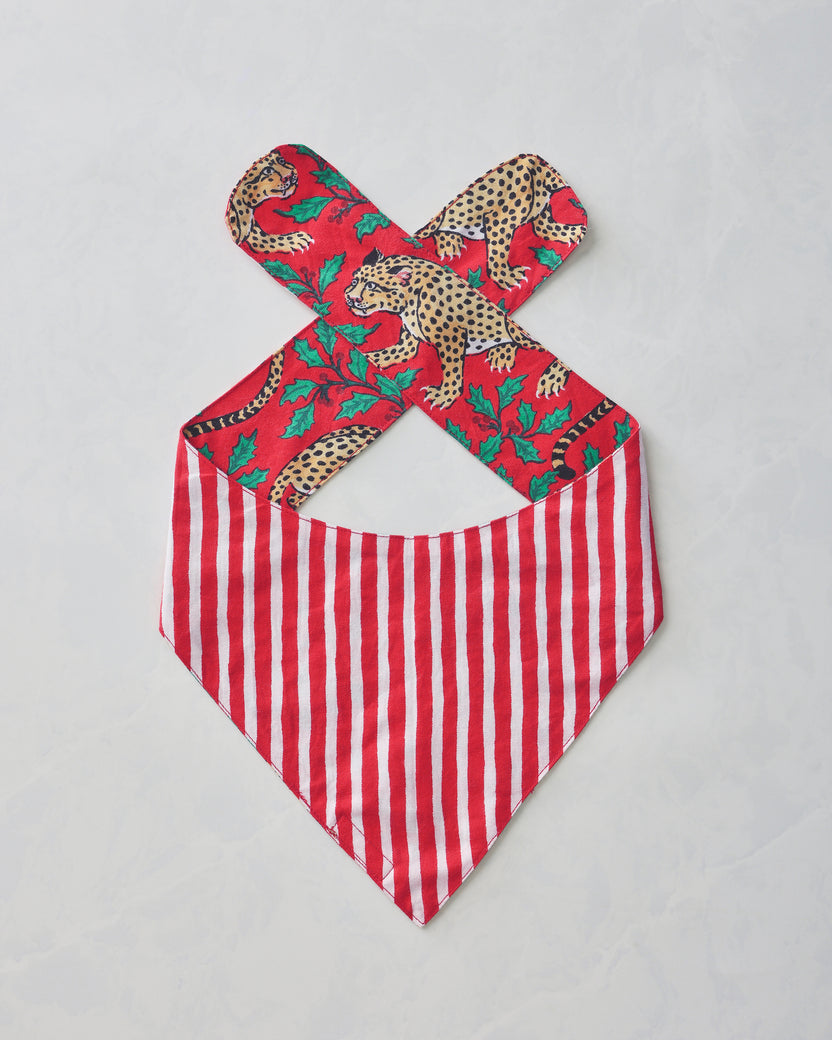 Winter Holly Bagheera pet bandana laid flat, with crossed ties, a red leopard-and-holly print, and a red-and-white striped pointed bib.