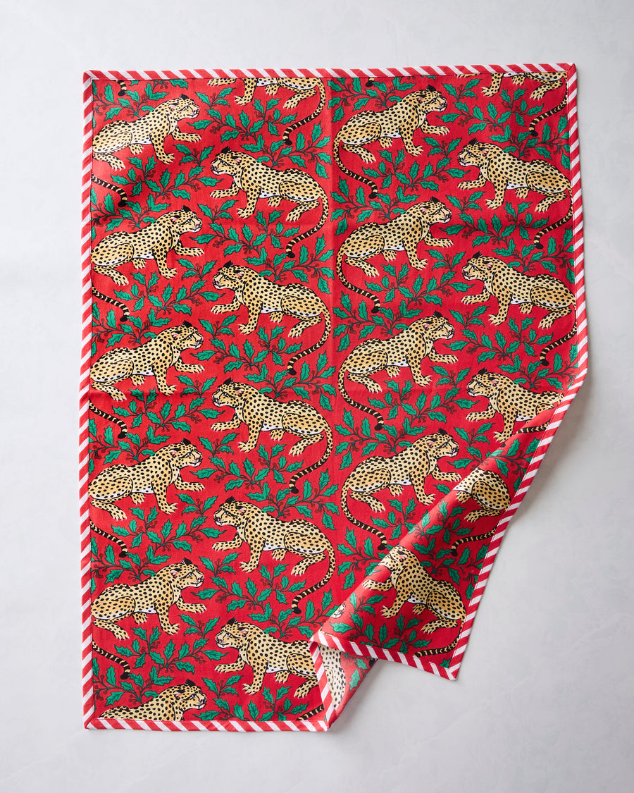 Front of a Winter Holly Bagheera tea towel with a red leopard-and-holly print and red-and-white striped border.