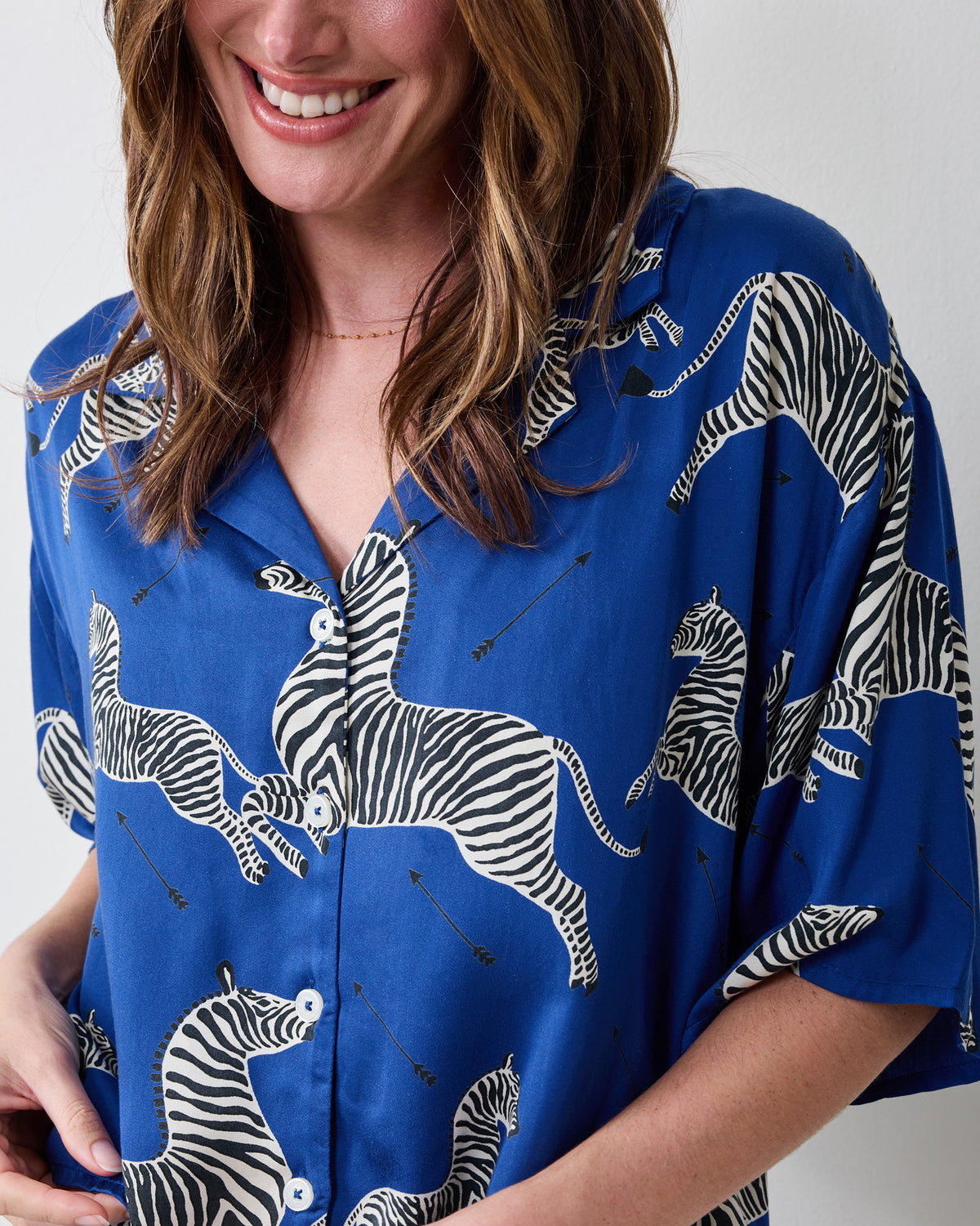 Close-up of the denim-blue zebra-print pajama top showing its collar, buttons, and short sleeves.