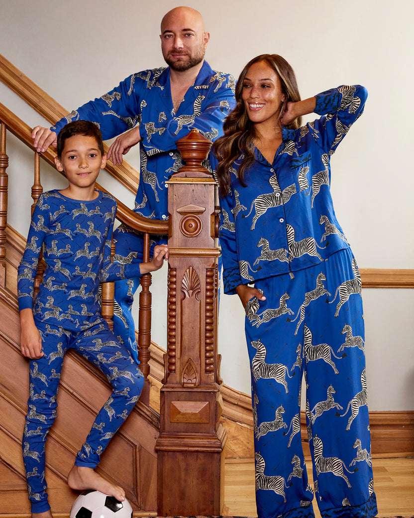 Three people wearing blue zebra-print pajamas pose together on a staircase.