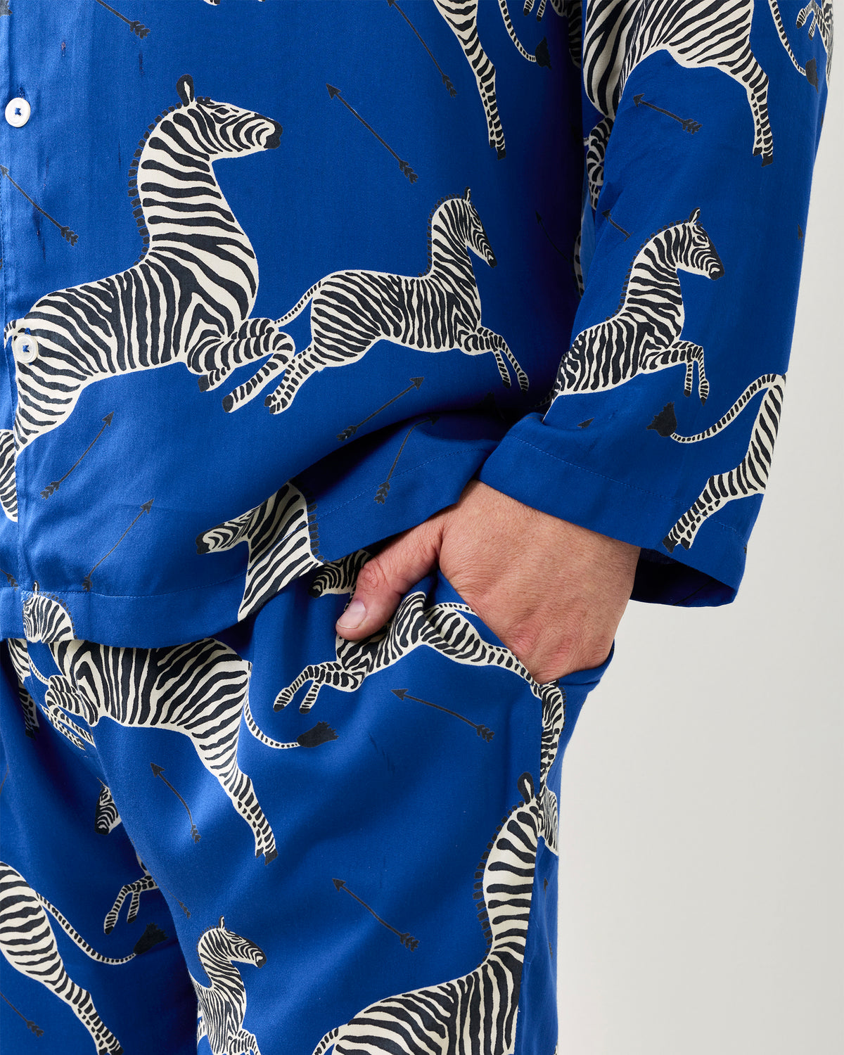 Close-up of the blue zebra-print pajama shirt and pants, showing the button placket, cuff, pocket, and hand in the pants pocket.
