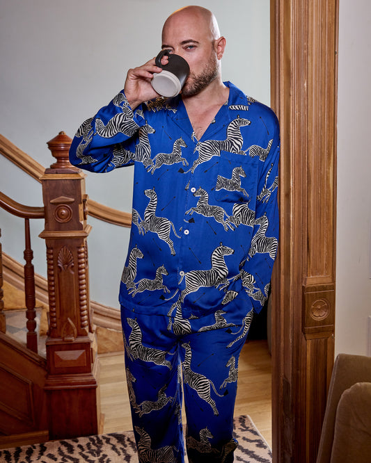 Adult model wearing a blue long-sleeve pajama set with white zebra prints and drinking from a mug.