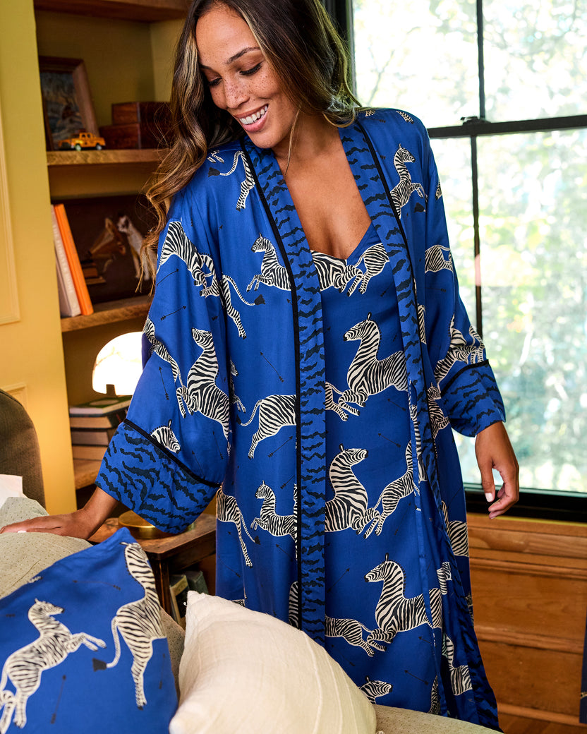 Person wearing a blue zebra-print robe with contrasting patterned trim and cuffs; a matching garment is visible underneath.