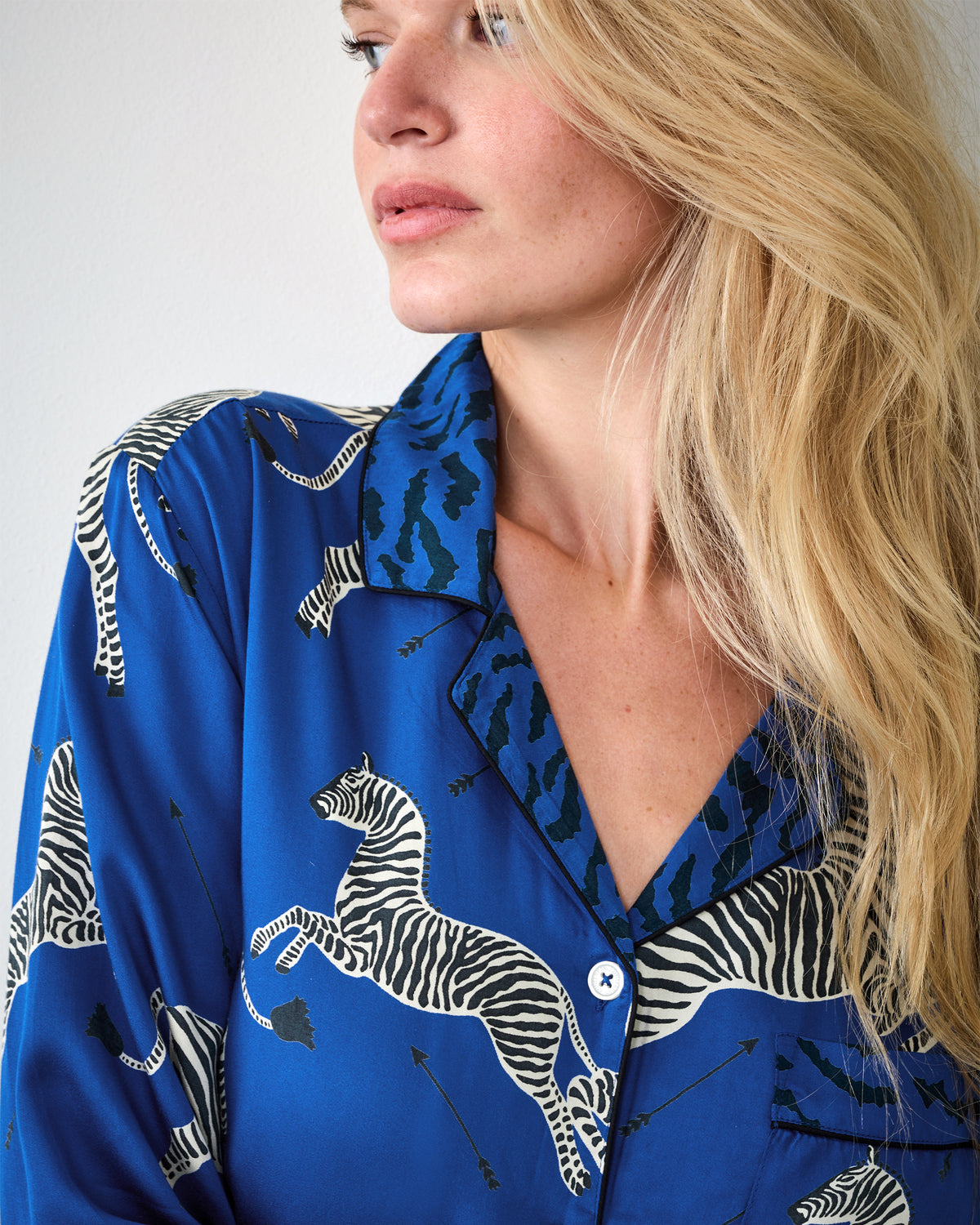 Close-up of a blue zebra-print pajama top with a notched collar, button front, and chest pocket.