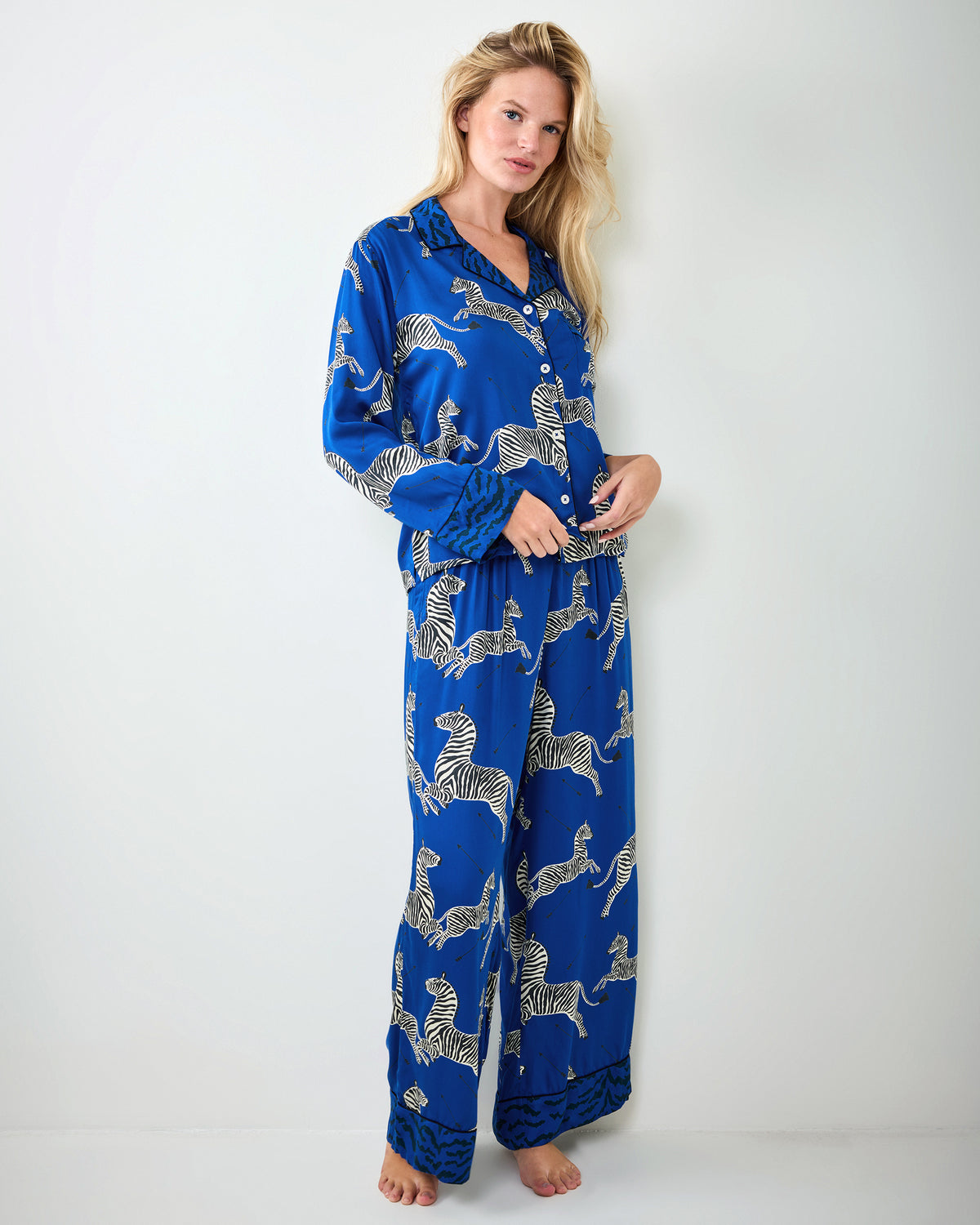 Person modeling a blue zebra-print long-sleeve pajama shirt and full-length pants, shown standing.