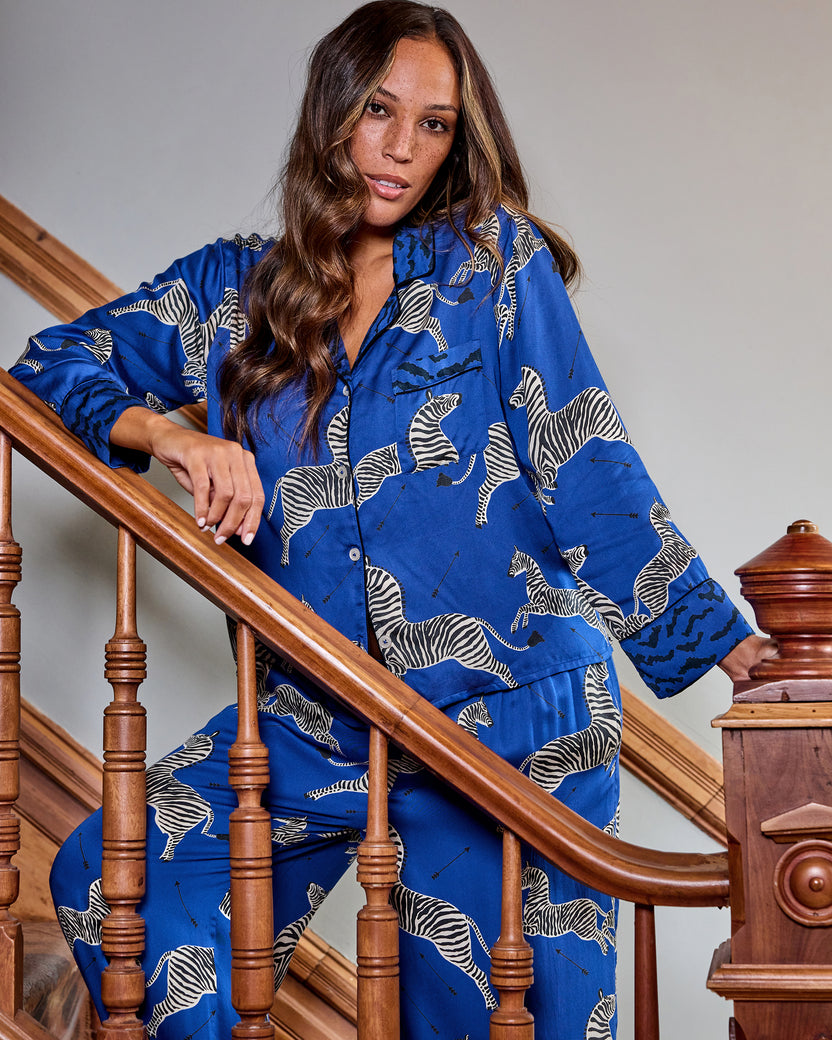 Person modeling a blue zebra-print long-sleeve pajama shirt and pants on a staircase.