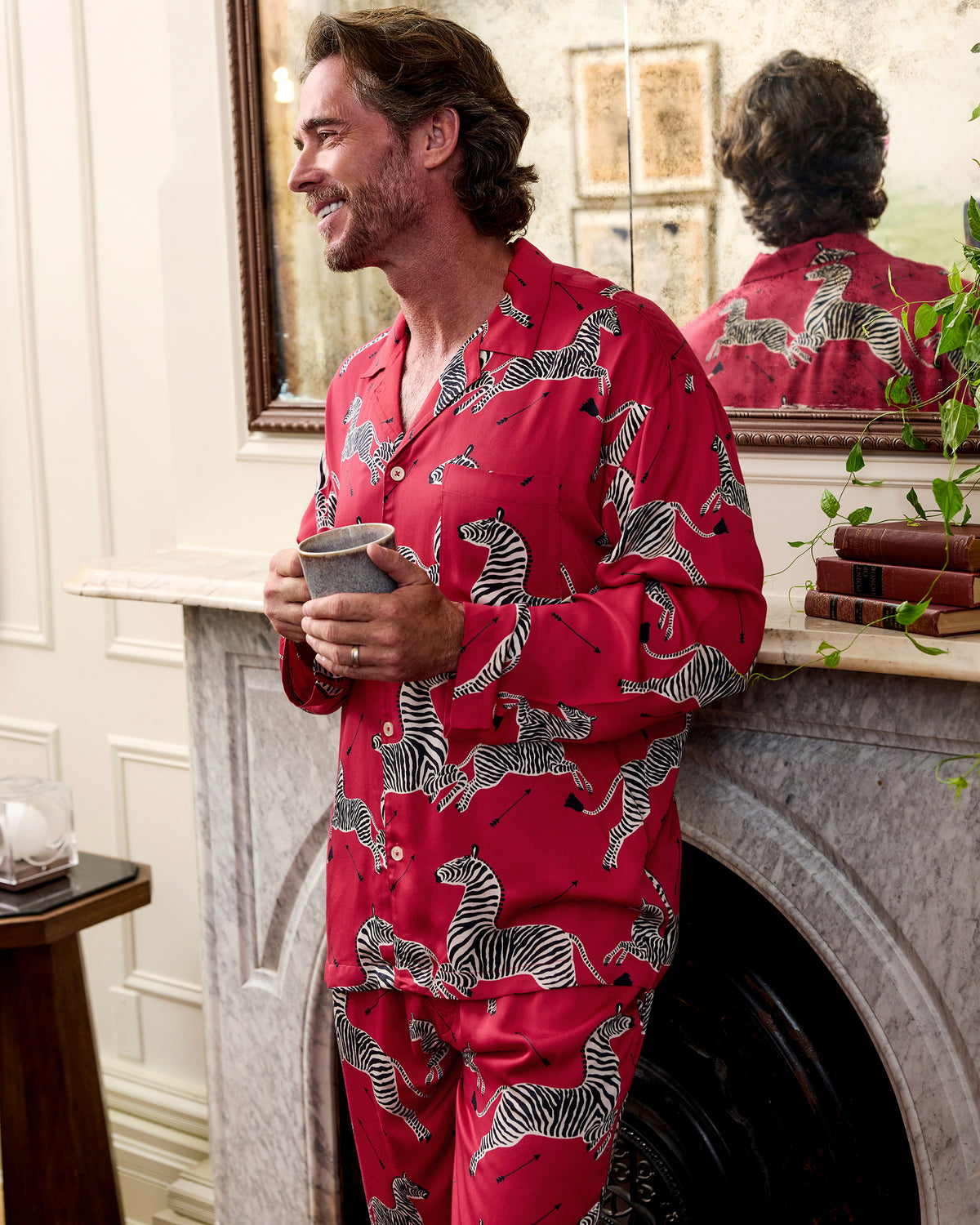 Three-quarter view of a person wearing a red zebra-print pajama shirt and pants while holding a mug.