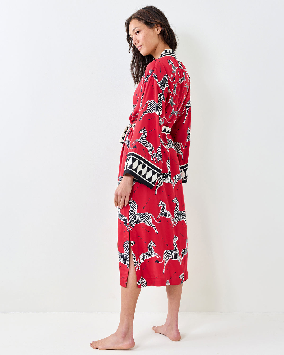 Side view of a person wearing a red zebra-print robe with a back slit and geometric sleeve trim.