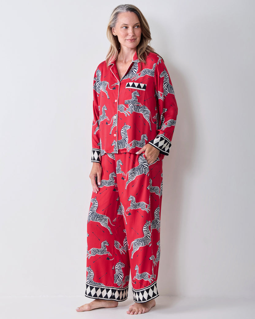 Front view of a person wearing a red zebra-print pajama shirt and wide-leg pants, barefoot.