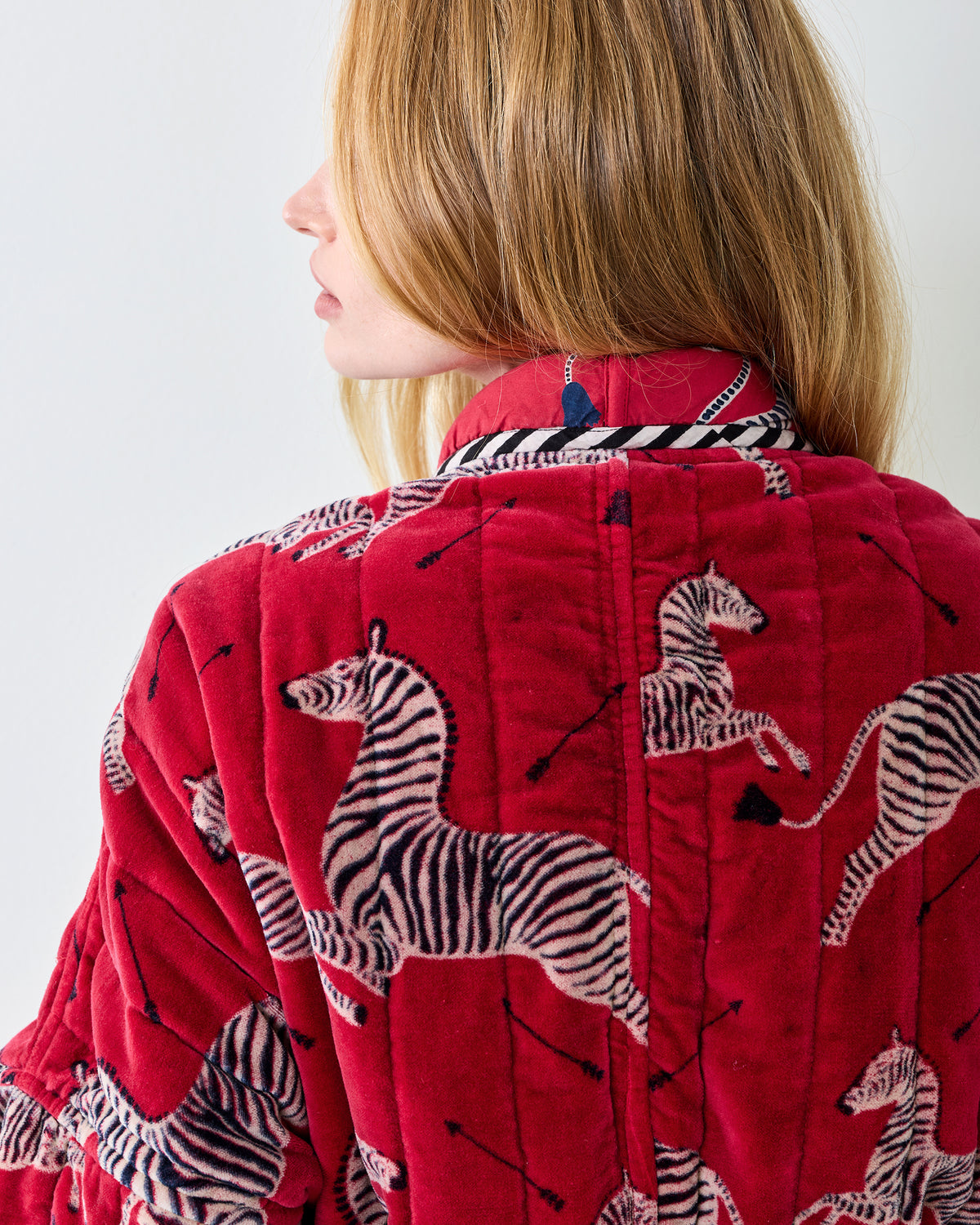 Close-up of the red zebra-print quilted robe showing the collar, back seam, and sleeve.