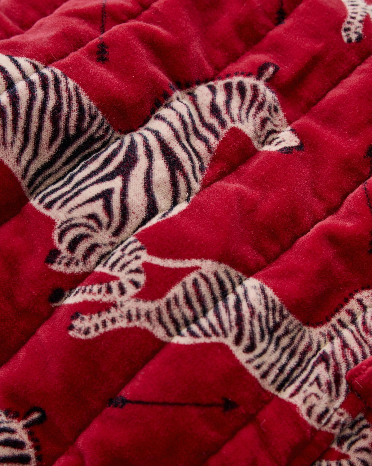 Close-up fabric detail showing the red quilted surface and zebra print.