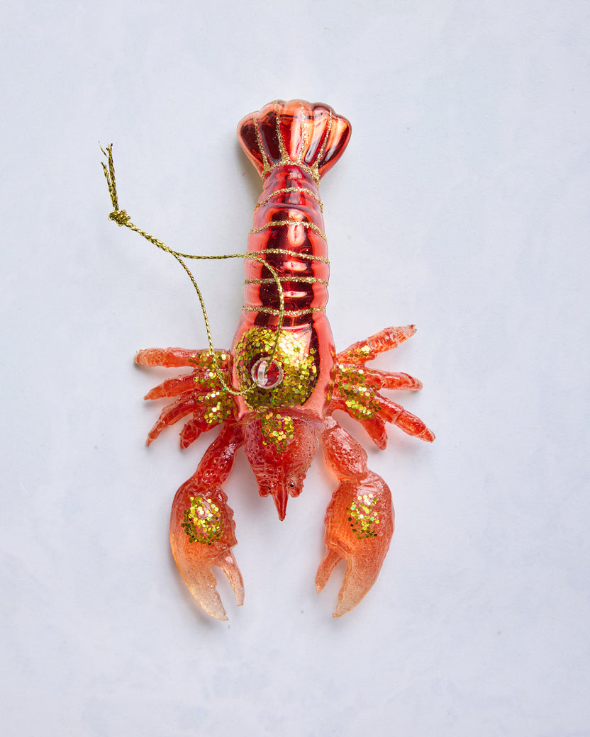 Top view of a red lobster glass ornament with glittered details and a hanging loop.