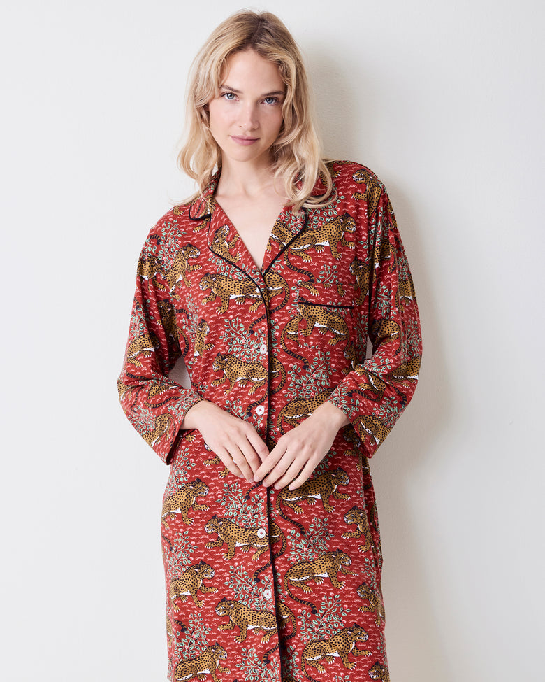 Front three-quarter view of a person wearing the Scarlet Bagheera long-sleeved sleep shirt with a notched collar, black piping, buttons, chest pocket, and leopard print.