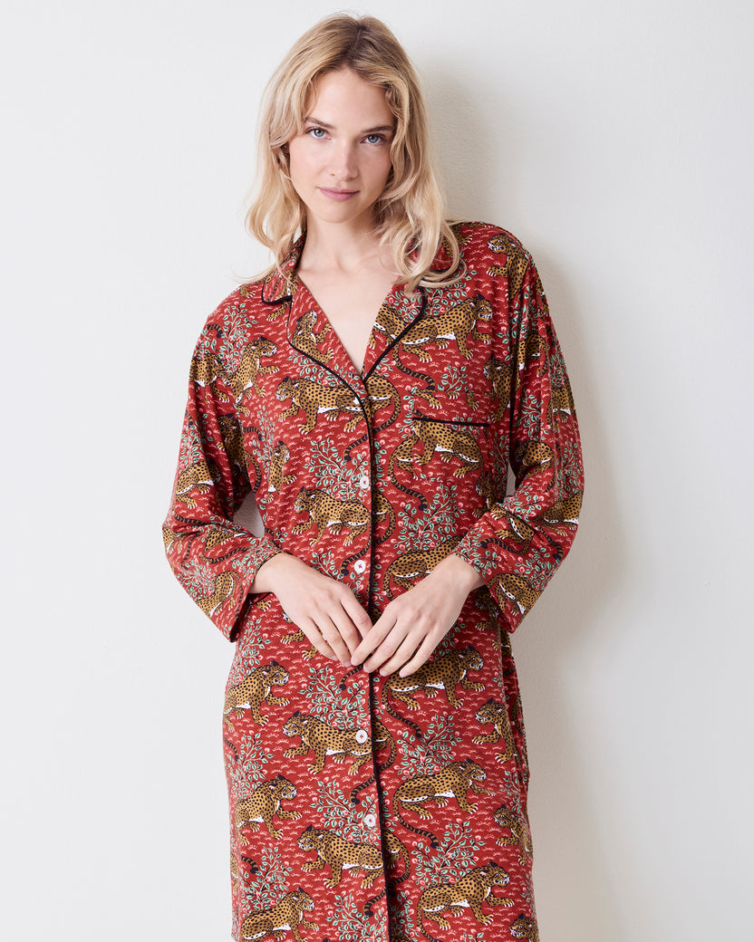 Front three-quarter view of a person wearing the Scarlet Bagheera long-sleeved sleep shirt with a notched collar, black piping, buttons, chest pocket, and leopard print.