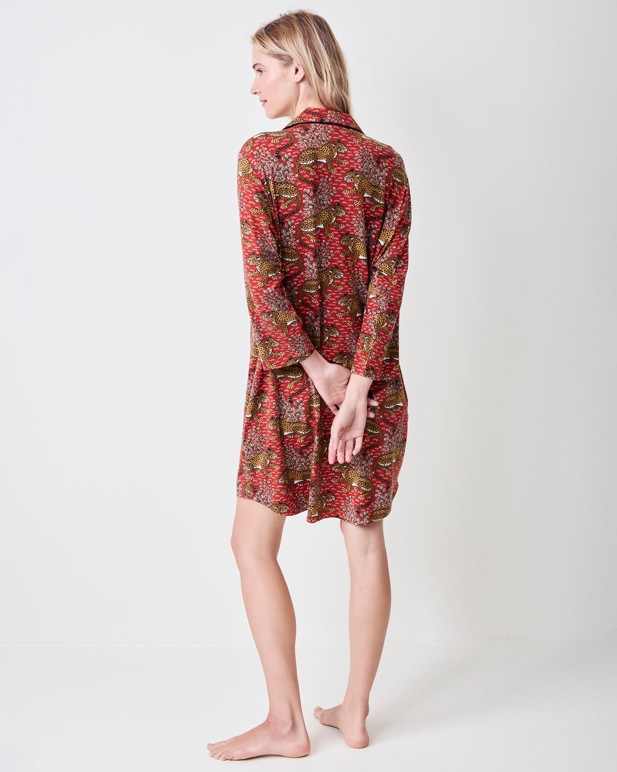 Back view of a person wearing the Scarlet Bagheera long-sleeved sleep shirt, showing the leopard and botanical print and black-piped collar.