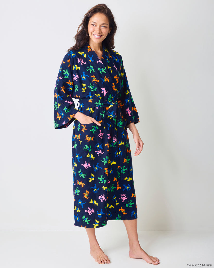 Front three-quarter view of a person wearing a long navy robe with a multicolor dancing-bear print, tie waist, and side pocket.