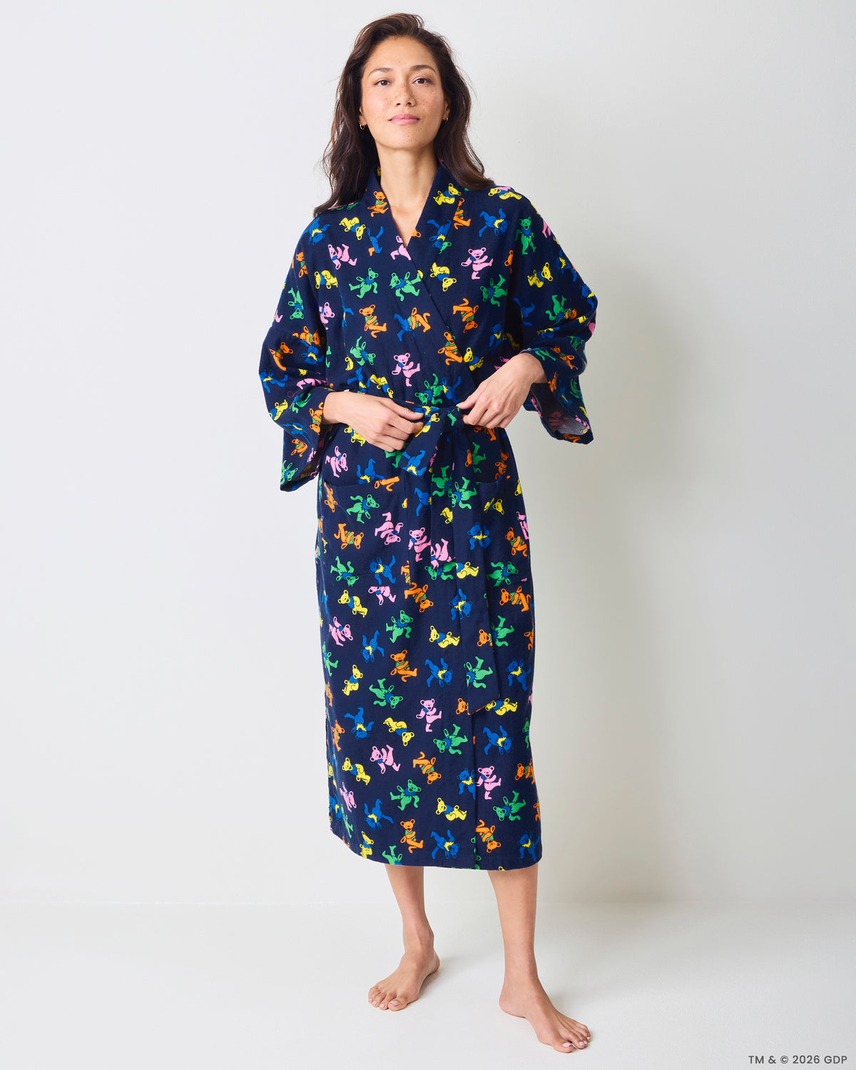 Front view of a person wearing a long navy robe with a multicolor dancing-bear print and tie waist.