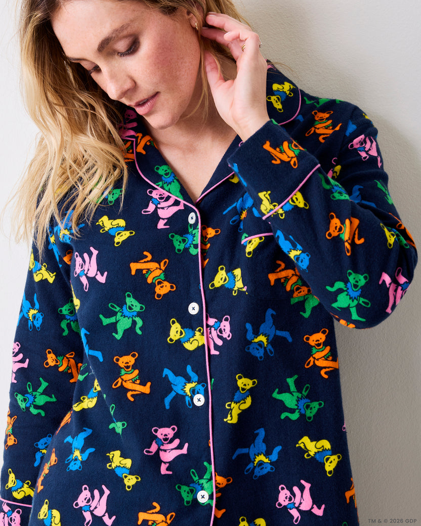 Close view of a navy Dancing Bears pajama shirt with colorful bear prints, pink piping, buttons, and long sleeves.