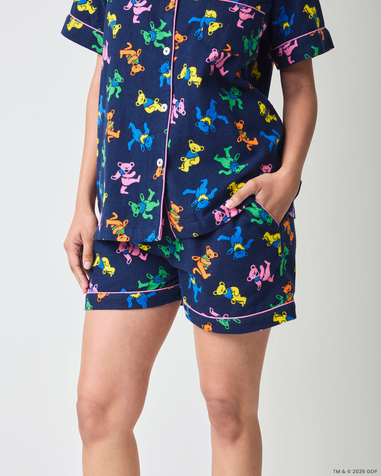 Close view of the short navy pajama set showing the printed button-front top and matching shorts with pink piping and pockets.