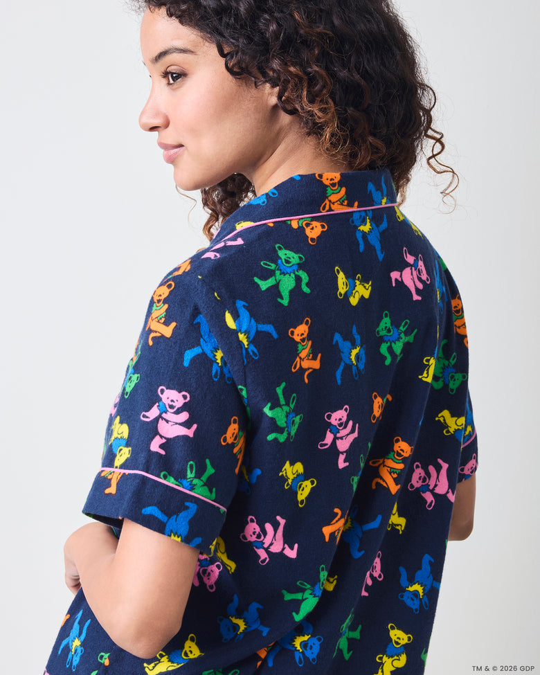 Back three-quarter close view of the short pajama top showing its collar, sleeve piping, and multicolor dancing-bear print.